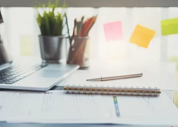 Stylo, carnet et ordinateur posés sur un bureau