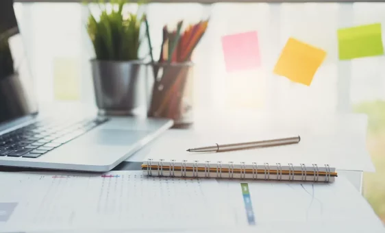 Stylo, carnet et ordinateur posés sur un bureau
