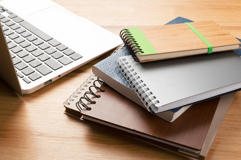 Un ordinateur portable et plusieurs carnets de notes posés sur une table